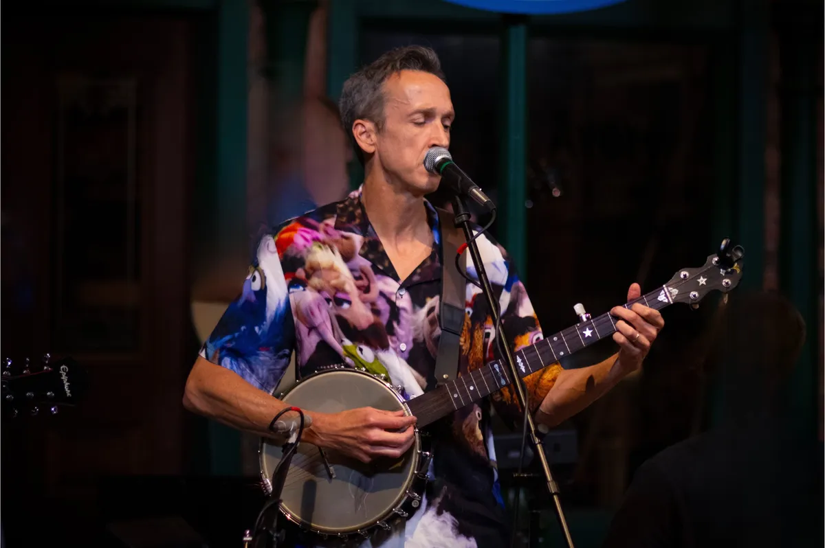 Josh Turknett singing and playing banjo on stage